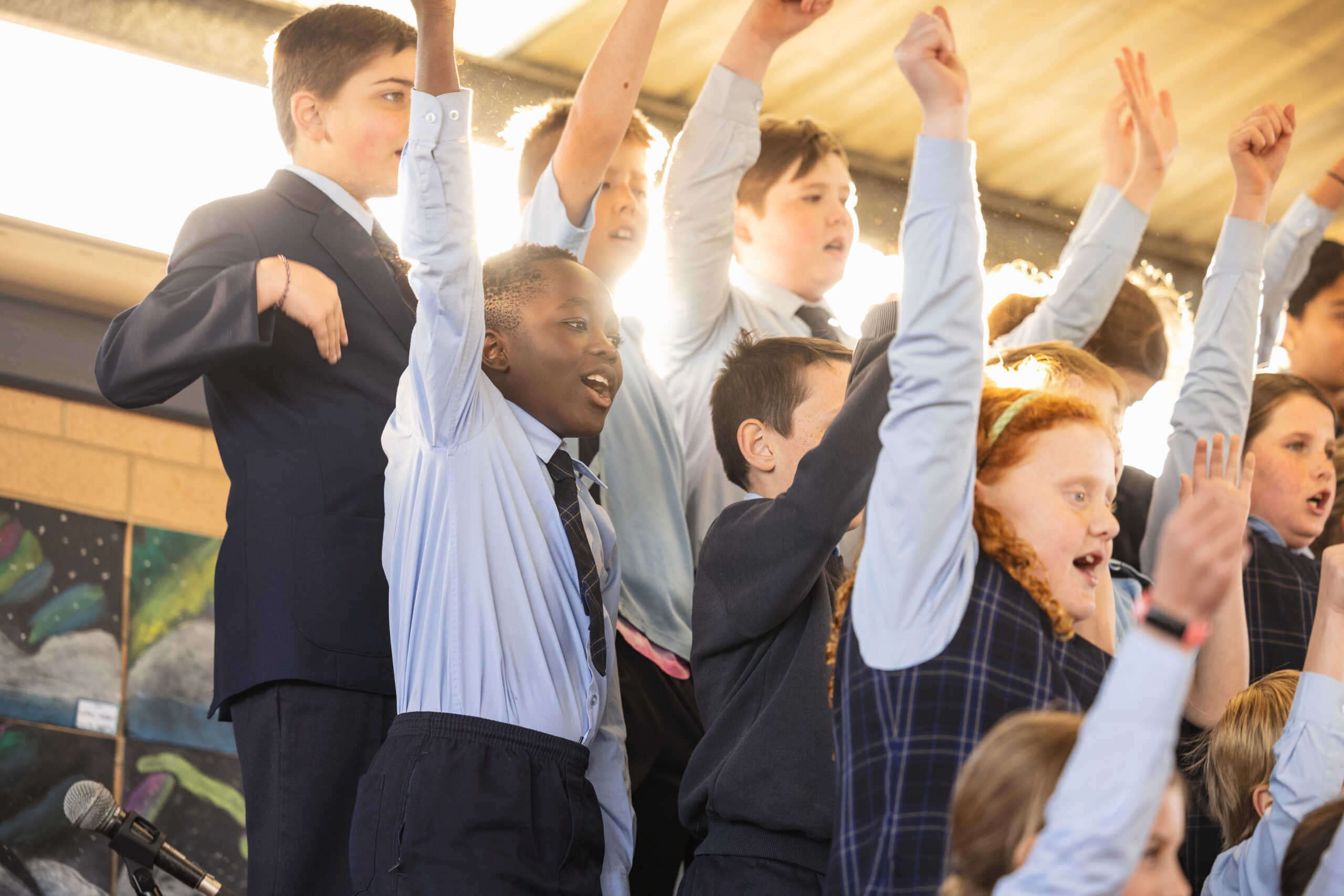 children raising arms in the air performing as part of the Junior School Choir